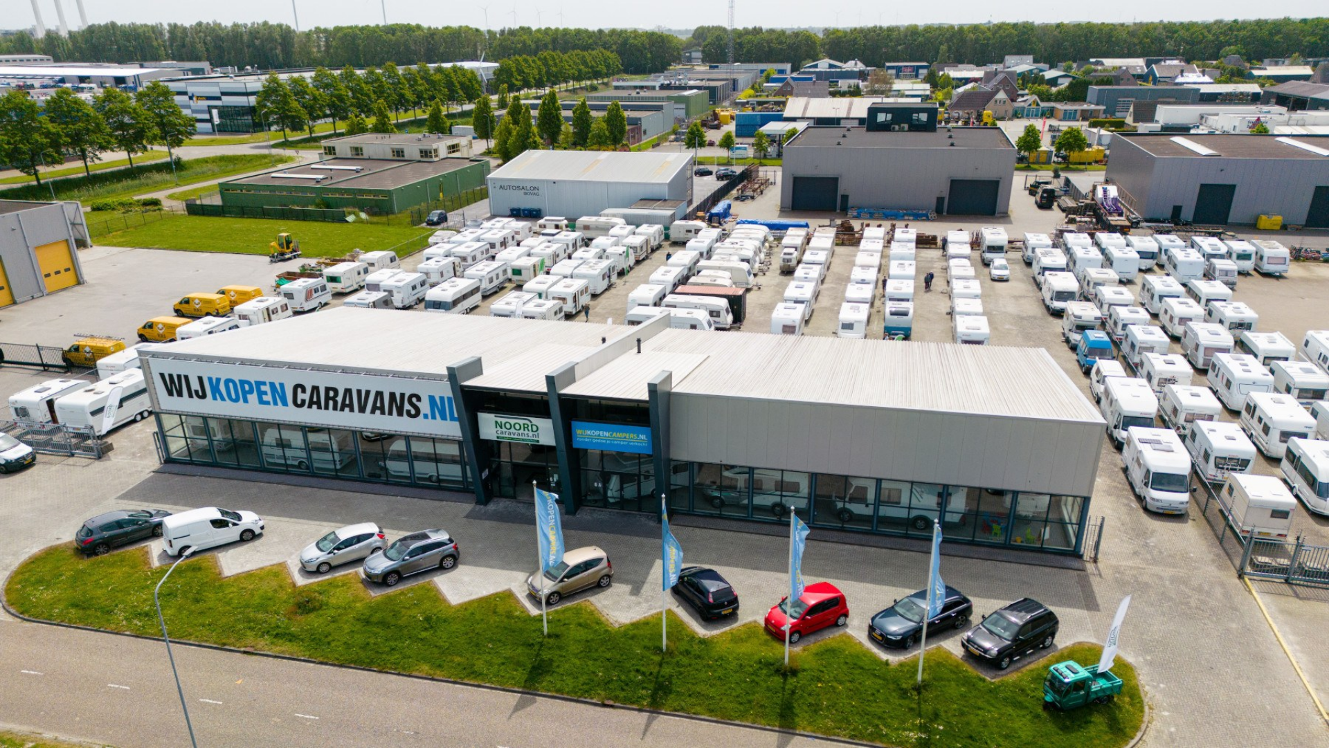 Luchtfoto van Noord Caravans met showroom, vlaggen en tientallen occasions op het buitenterrein.